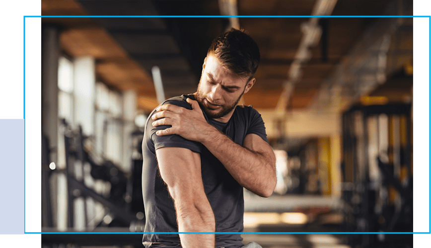 A man holding his shoulder in the gym