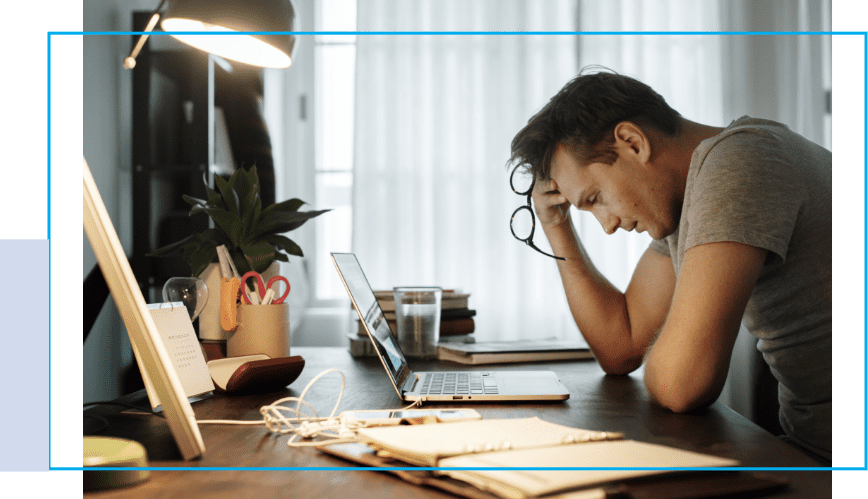 A man sitting at his desk with his head in his hand.