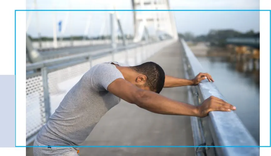 A man leaning on the railing of a bridge.