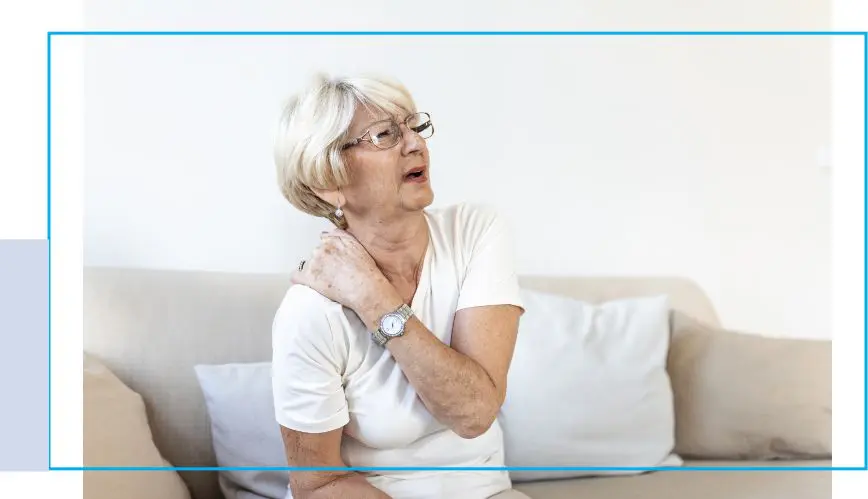 A woman sitting on the couch holding her neck.